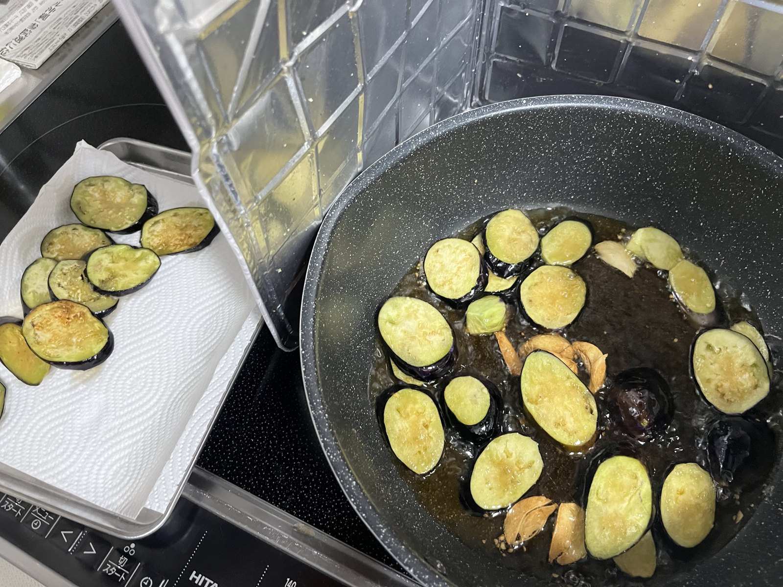 フライパンで揚げ焼きにする茄子とニンニクスライス